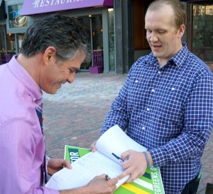 Former State Senator Ethan Strimling signs Tom MacMillan's petition for a $15 minimum wage.
