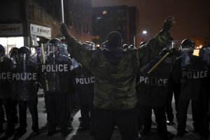 A demonstrator raises his arms as he faces law enforcement officers near Baltimore Police Department Western District during a protest against the death of Freddie Gray in police custody, in Baltimore