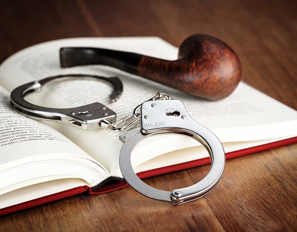 West End News - Book Nook Mysteries - Mystery book with pipe and handcuffs