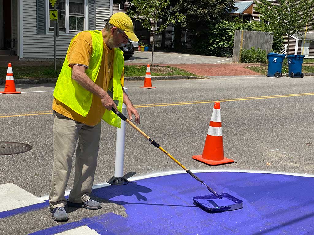 Gregory Farino paints the crosswalk as part of traffic calming efforts put forth by WENA, Portland Trails