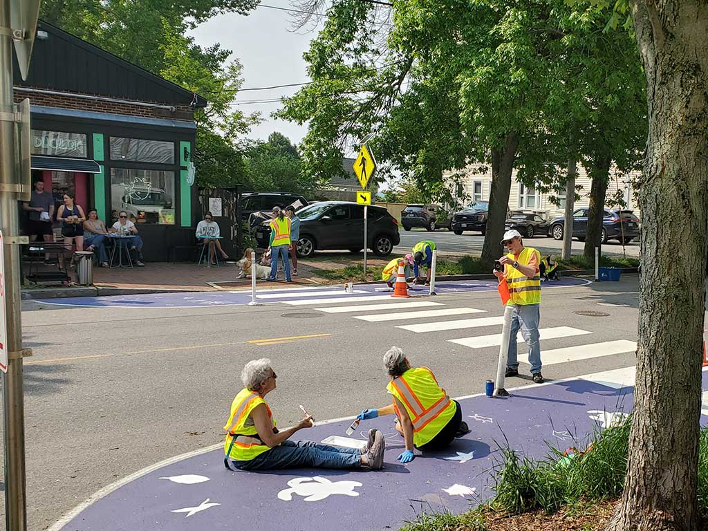 Volunteers paint crosswalk bump outs