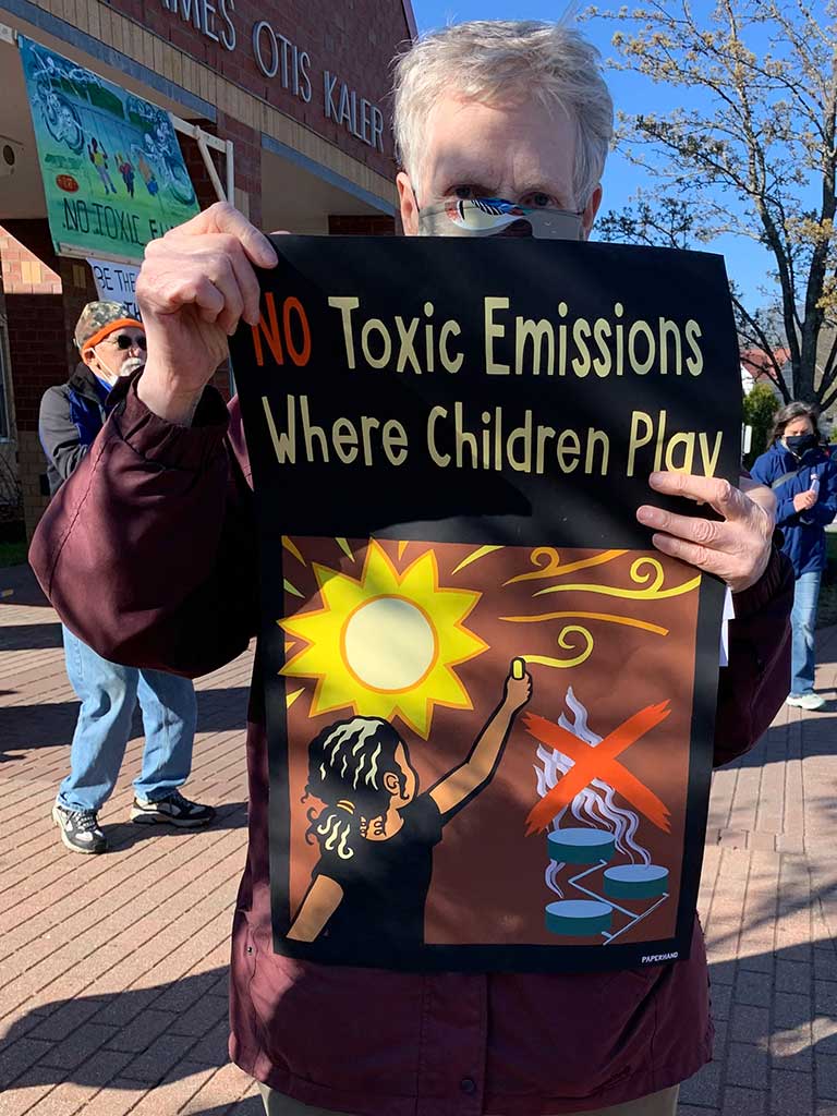 West End News - Battle for Clear Skies - Rachel Burger holding 'No Toxic Emissions' sign - By Karen Silverman, 2021