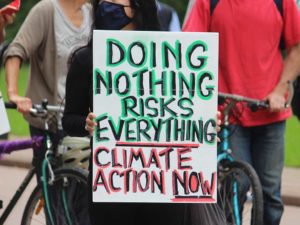 Adobe Stock climate protest - Sign reads, "Doing nothing risks everything..."