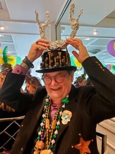 Layne Witherell at Commanders Palace with festive Mardis Gras hat and flare