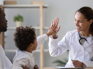 Doctor high fives child patient with father 