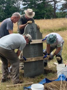 Volunteers restore a grave marker at Western Cemetery