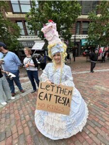 Rallly goer at No Kings in Monument Square with sign "Let them Eat Tesla"